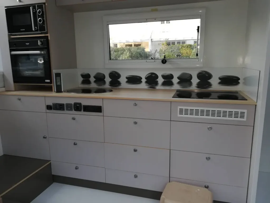 Kompakte Küchenzeile in einem Selbstausbau-Camper mit Mikrowelle, Ofen und Induktionskochfeldern.