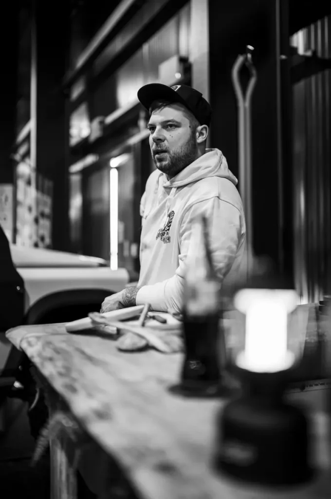 Ein Mann im Hoodie fertigt Holzarbeiten für einen Selbstausbau am Tisch.