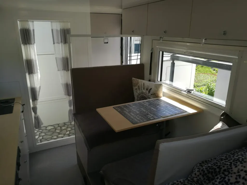 Heller Innenraum eines Selbstausbau-Campers mit Dinette, Stauraum und Ausstellfenster.