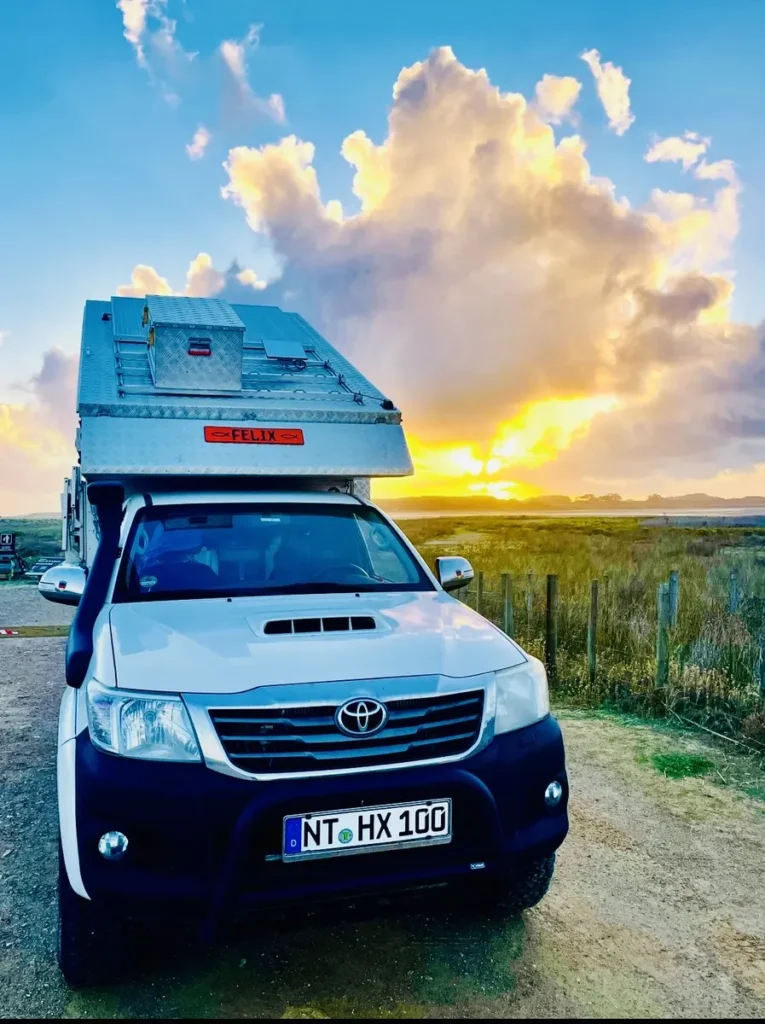 Expeditionsmobil auf Toyota Hilux Basis mit Wohnkabine bei Sonnenuntergang.