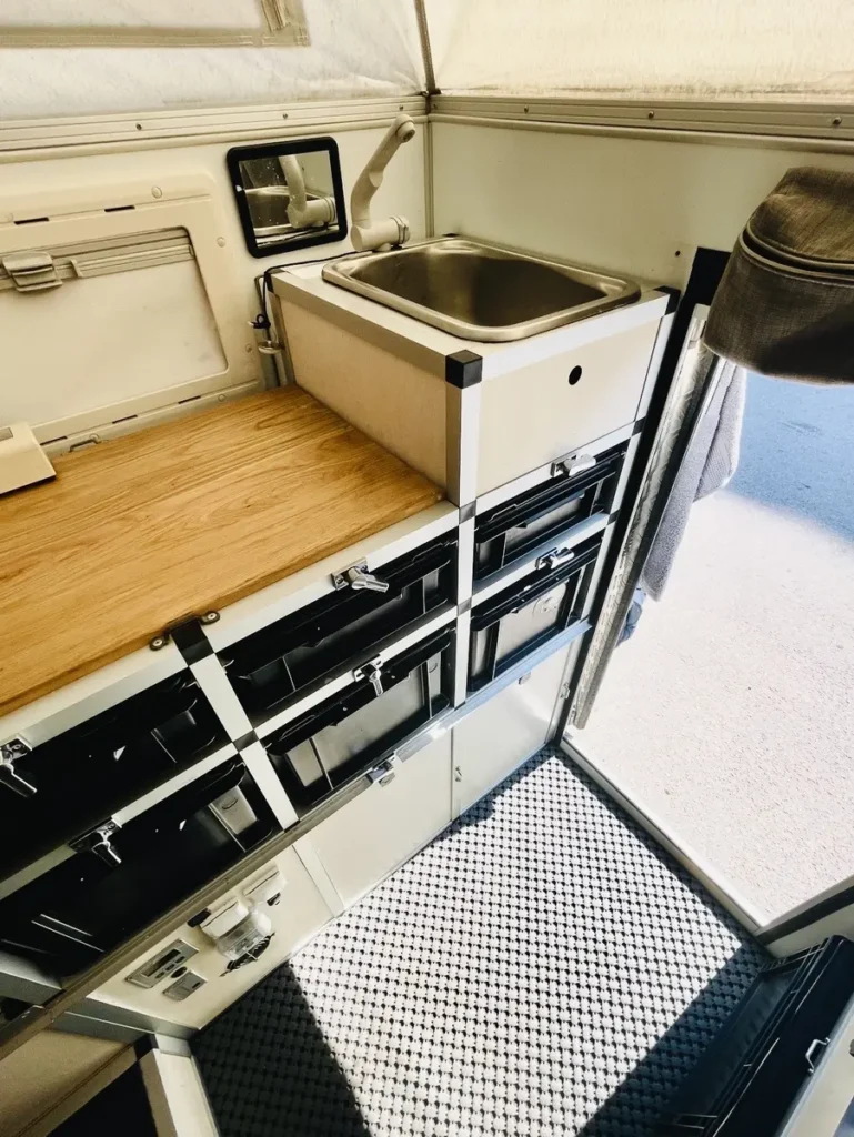 Modulare Kücheneinheit im Innenraum eines Pop-top Campers mit Spüle und Stauraum.