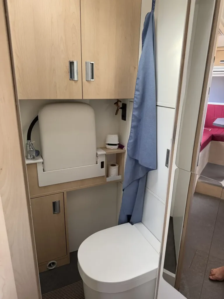 Kompakte Nasszelle mit Toilette, Spiegelschrank und Holzelementen in einem Selbstausbau Campervan.
