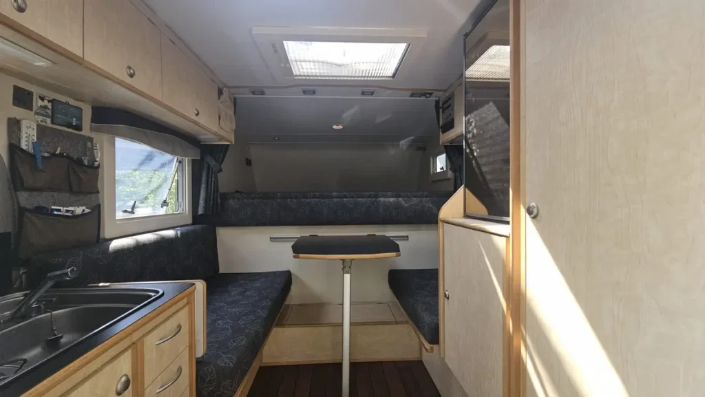 Der helle Innenraum einer Pick-up Wohnkabine mit Kochnische, Sitzecke, Betten und Dachluke.