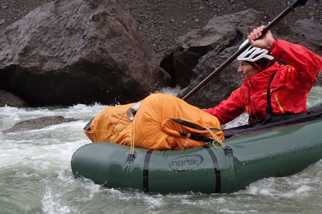 Packrafting auf einem Wildwasserfluss mit felsiger Uferlandschaft.