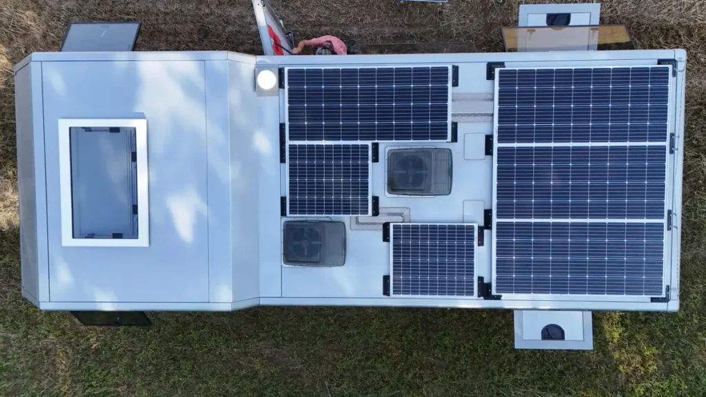 Draufsicht auf ein graues Expeditionsmobil mit mehreren Solarmodulen, Dachluke und Lüftern.