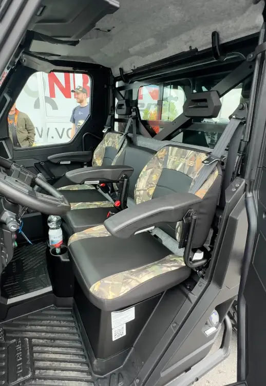 Robuster Innenraum eines Offroad-Fahrzeugs mit zwei Sitzreihen und Camouflage-Polstern.
