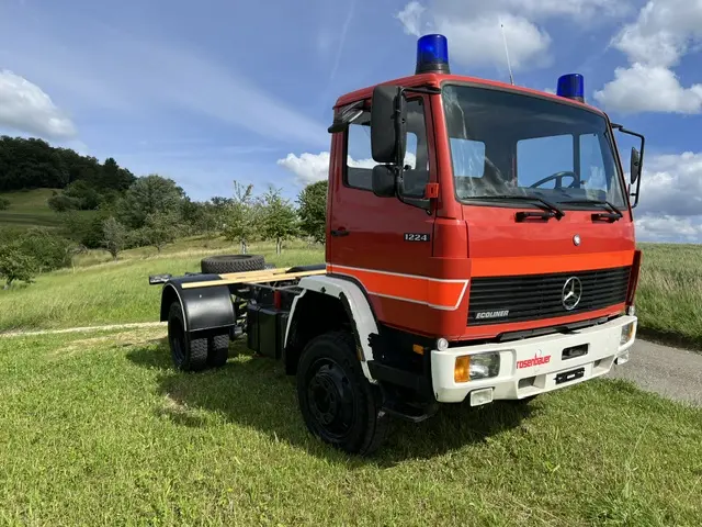 Rotes Mercedes-Benz Ecoliner LKW-Fahrgestell mit Blaulicht auf einer Wiese für den Expeditionsmobil-Selbstausbau.