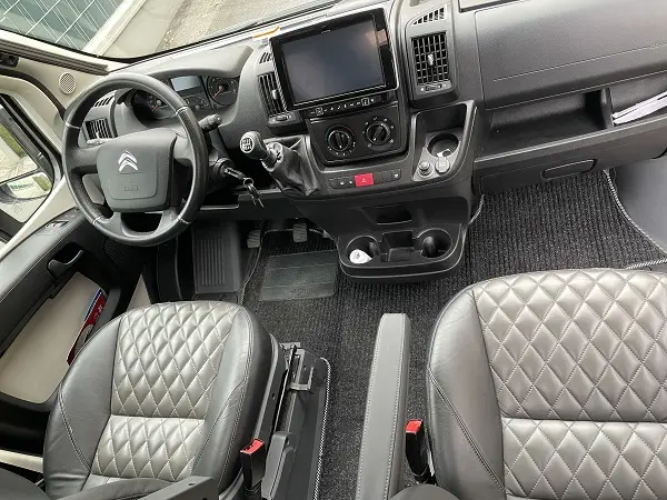 Innenraum eines Campervans mit Citroën-Lenkrad, großem Infotainment und gesteppten Ledersitzen.