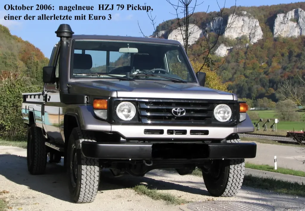 Ein grauer Toyota Land Cruiser HZJ 79 Pickup mit Schnorchel auf einem Offroad-Weg.