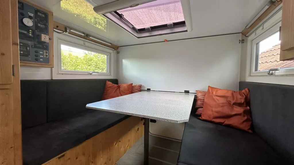 Sitzgruppe und Tisch in einem Expeditionsmobil-Innenausbau mit Dachluke.