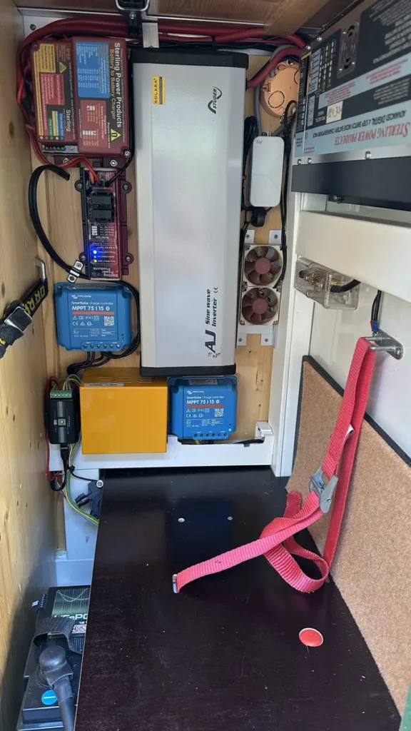 Detaillierte Ansicht der Elektroinstallation mit Solarladereglern, Wechselrichtern und Batterieladegerät in einem Camper-Ausbau.