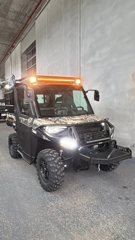 Schwarzes Polaris Ranger UTV mit Tarnmuster und umfangreicher Offroad-Beleuchtung.