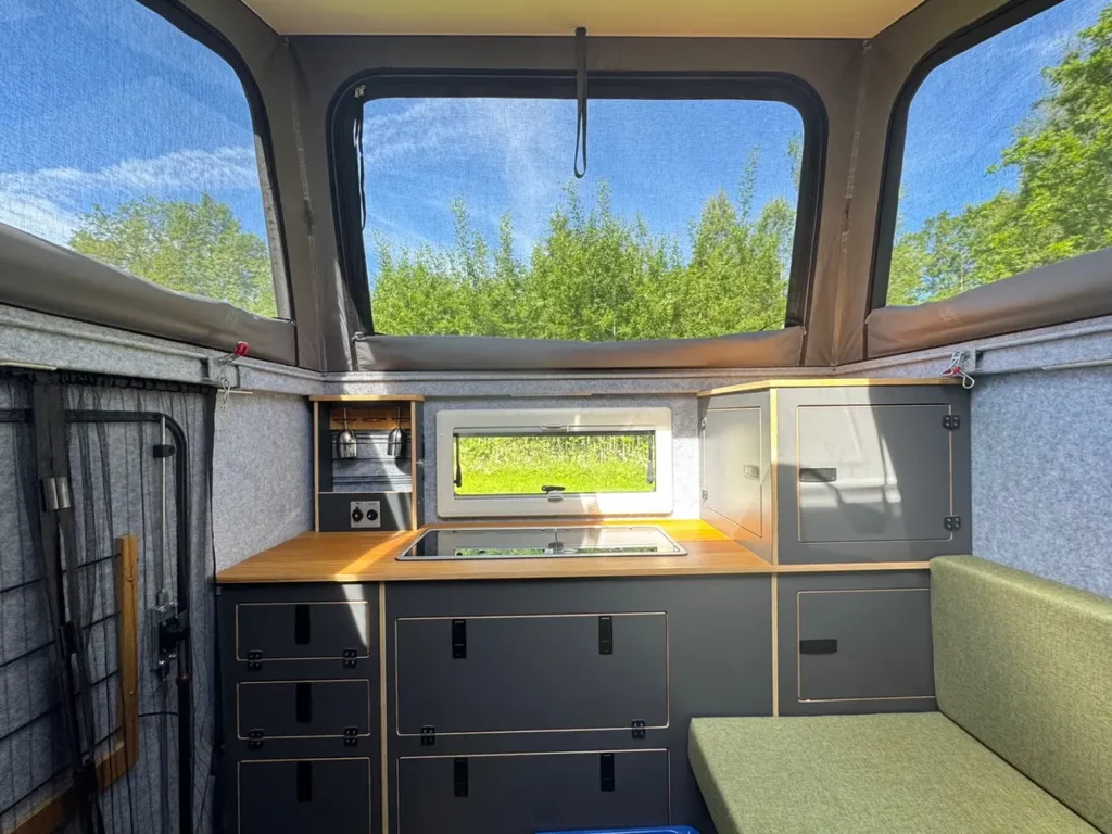 Innenansicht eines selbstausgebauten Campervans mit Küchenzeile und Aufstelldach.