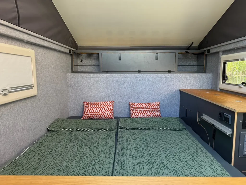 Inneneinrichtung eines Selbstausbau-Campers mit Bett, Stauraum und Aufstelldach.
